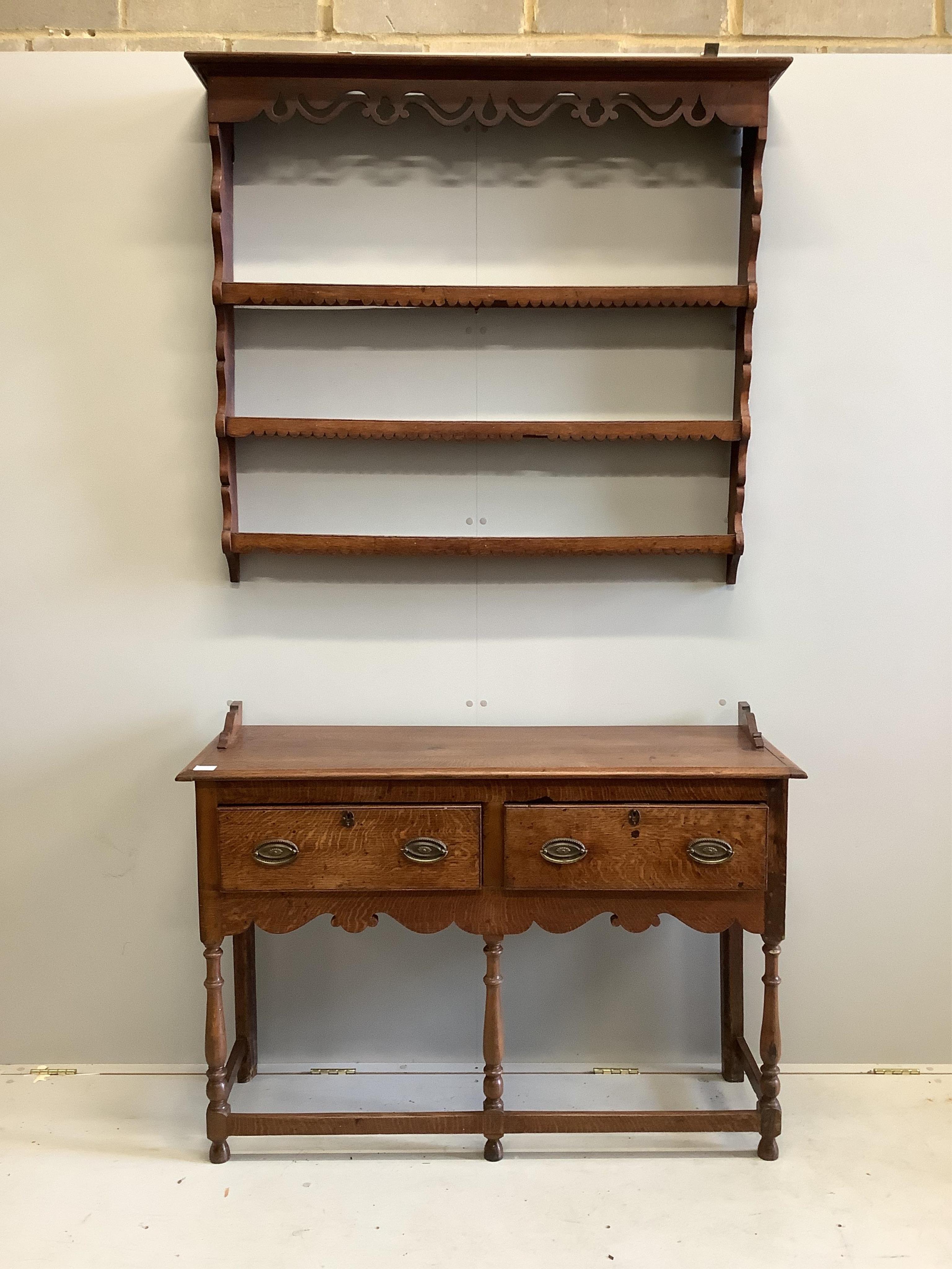 A George III style oak dresser, of small proportions, fitted with twin drawers and shaped apron, raised on turned supports, together with an associated wall rack, width 155cm, depth 44cm, height 196cm. Condition - fair